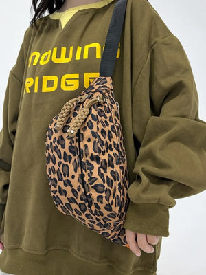 Pleated leopard print sling bag with rope detail and black strap.