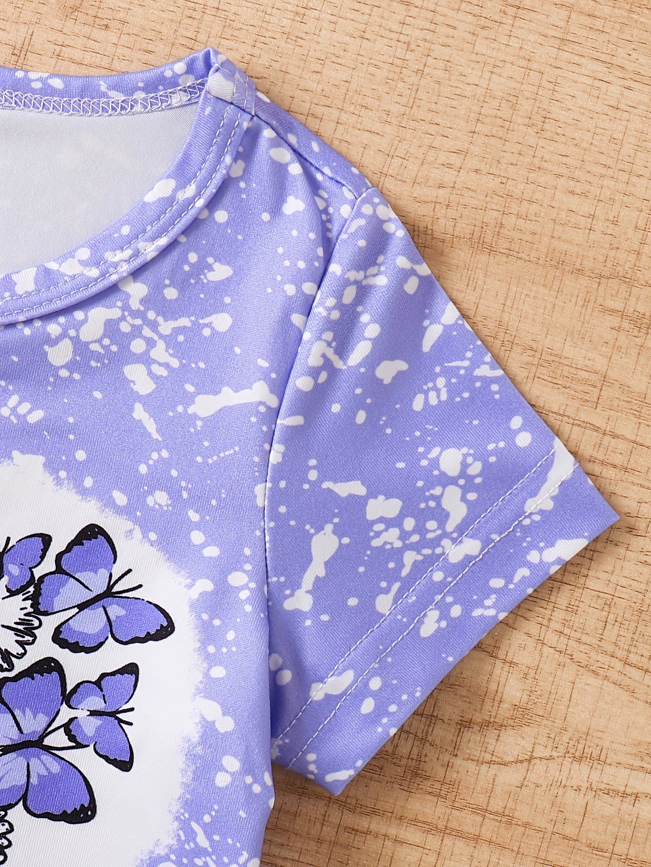Children's purple butterfly graphic tee with white splatter print and short sleeves.