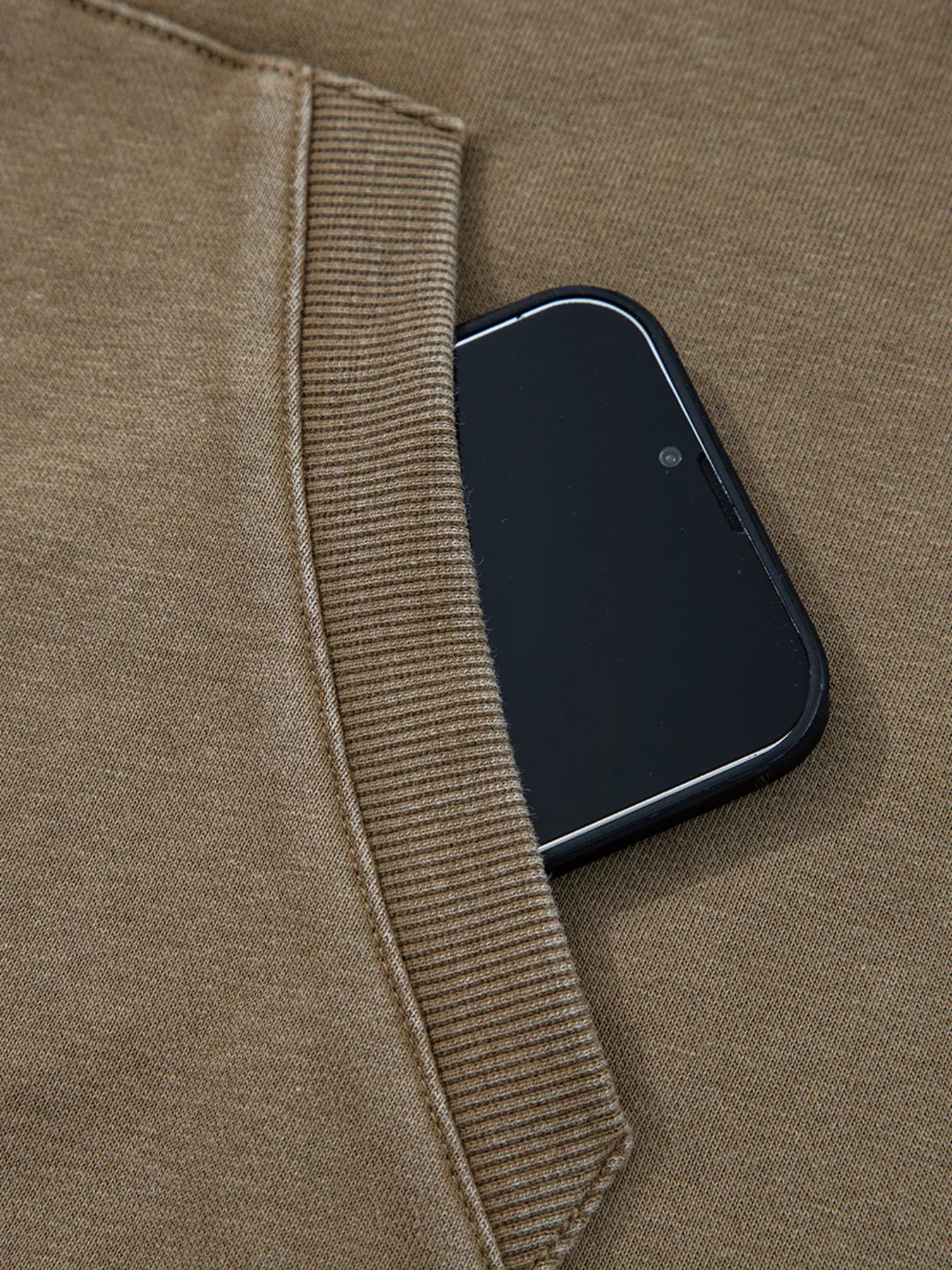 Mineral wash coffee brown hoodie with a phone in the pocket and ribbed trim detail.