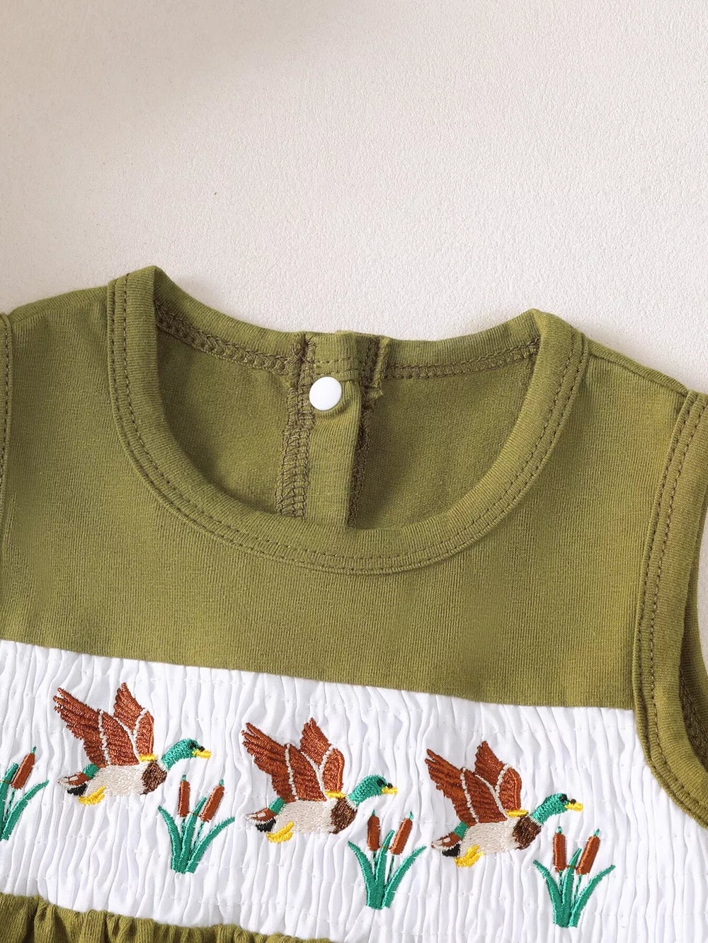 Baby girls' olive green tank top with embroidered ducks and smocked white panel.