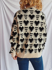 Geometric heart jacquard knit jumper in tan with black hearts and stripes pattern.