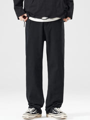 Men's black wide-leg jeans with a relaxed fit, styled with a white t-shirt and sneakers.