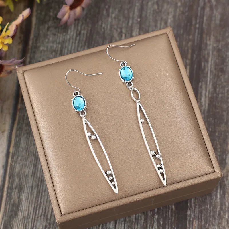 Silver dangle earrings with azure oval stones and elongated leaf-shaped drops.