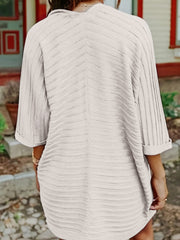 Textured ribbed sleeve cardigan in a light neutral color with a V-neckline and cuffed sleeves.