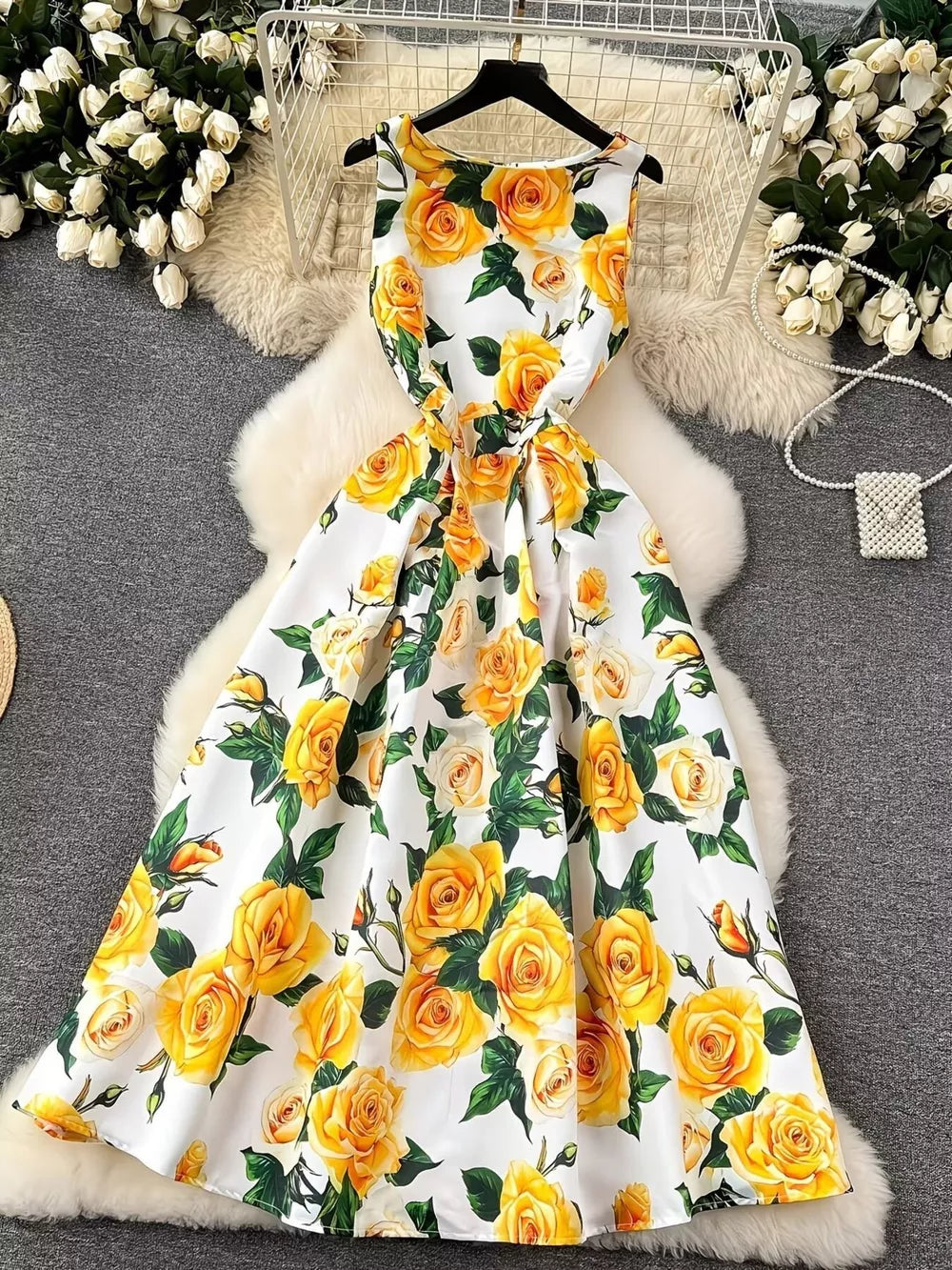 Yellow floral midi dress with pleated skirt and sleeveless design.