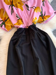 Pink abstract floral print romper with black wide-leg pants and pockets.