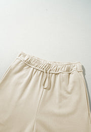 Beige wide-leg drawstring lounge pants with elastic waistband and tie detail.