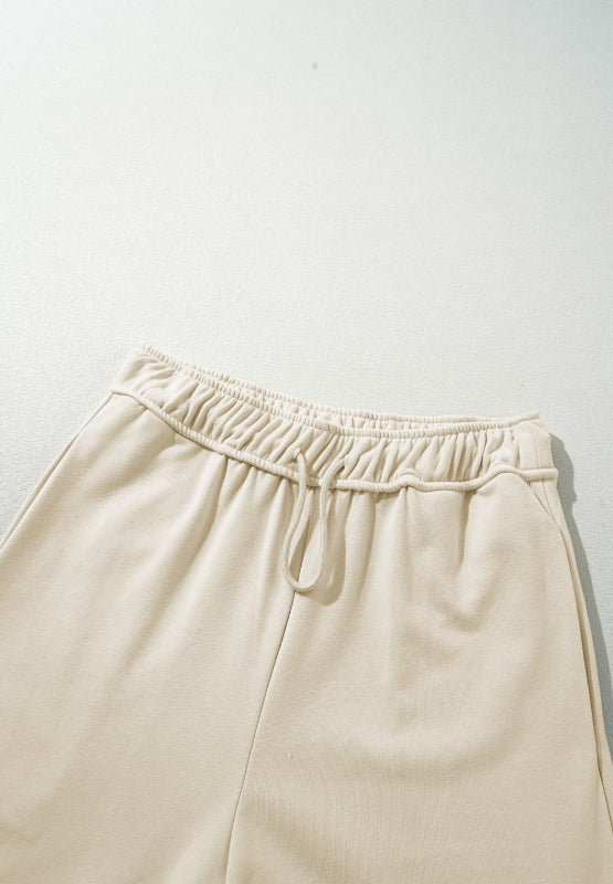 Beige wide-leg drawstring lounge pants with elastic waistband and tie detail.
