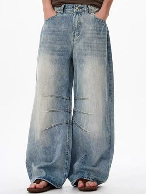Men's light wash denim wide leg jeans with exaggerated fit and panel details.