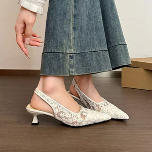 White lace slingback kitten heels with floral pattern and pointed toe.