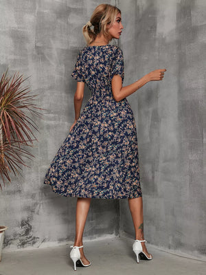 Dark blue midi dress with a vibrant floral leaf pattern, short sleeves, and A-line skirt.