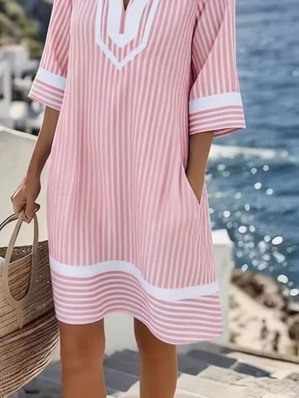 Pink striped V-neck dress with white trim and pockets, short sleeves.