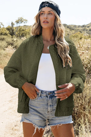 Moss quilted bomber jacket with a zip front and crew neck, styled with denim shorts.