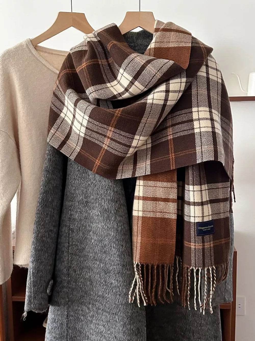 Plaid fringe scarf in brown, tan, and cream with fringed edges.