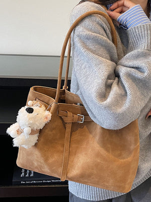 Brown suede shoulder bag with buckle accent and fluffy bear charm