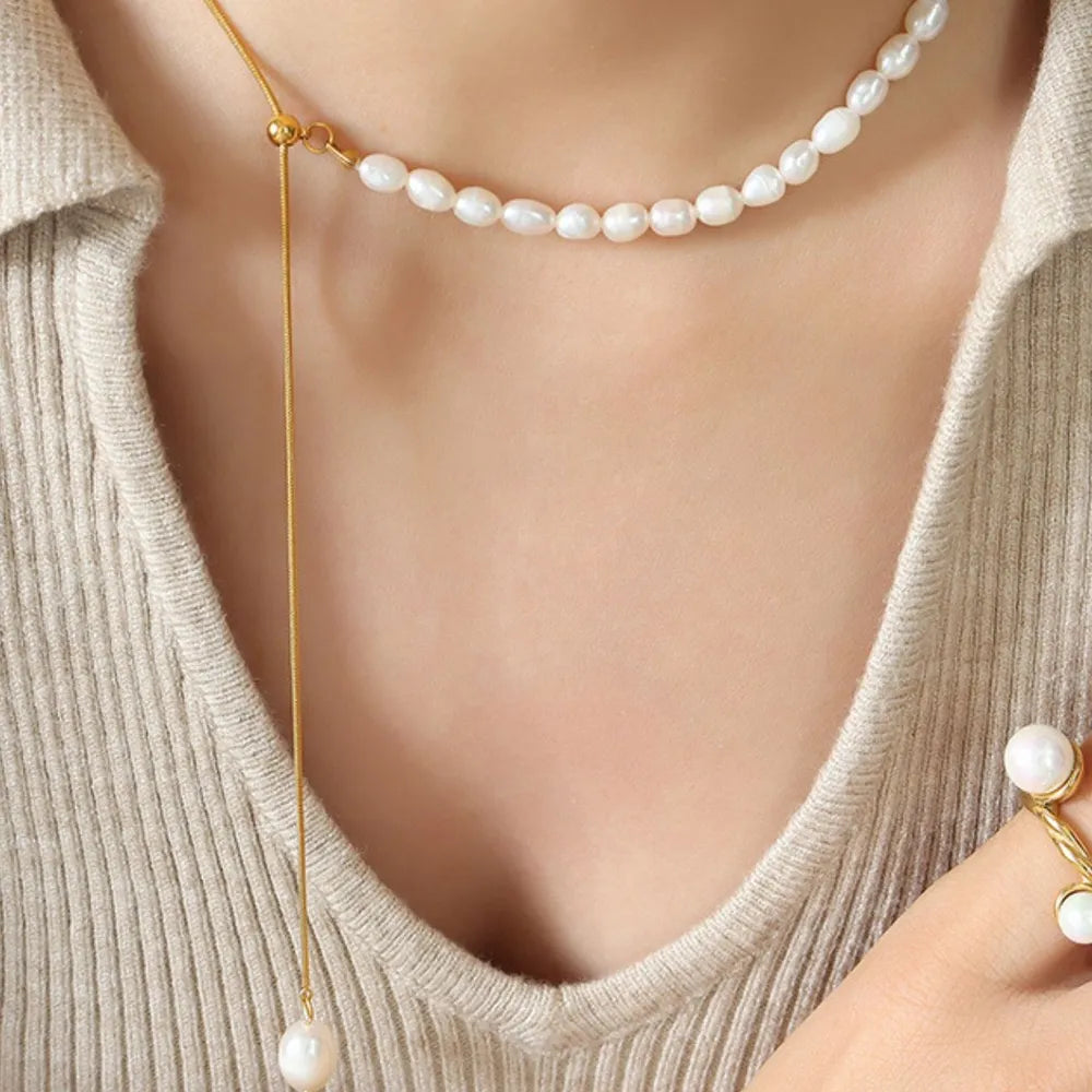 Gold asymmetrical pearl lariat necklace with adjustable chain and single pearl drop.