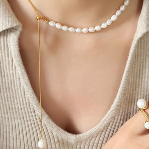 Gold asymmetrical pearl lariat necklace with adjustable chain and single pearl drop.