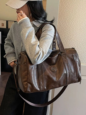 Brown pu leather duffel bag with zippered pockets and a circular logo detail.