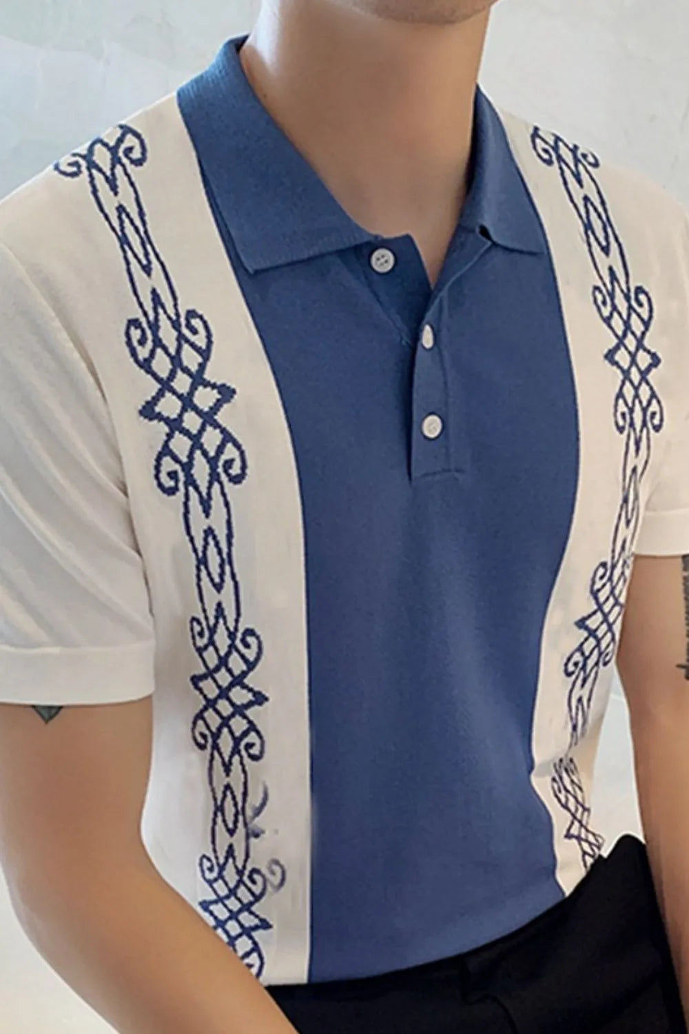 Embroidered panel polo shirt in dusty blue and white with ornate blue stitching details.