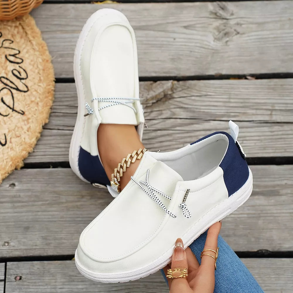 Chic white slip-on shoes with blue accents and decorative laces.