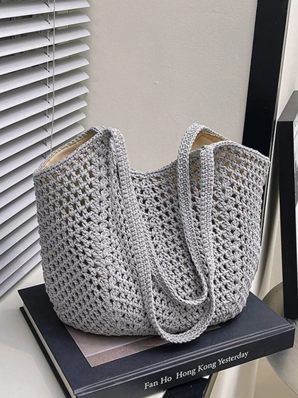 Grey woven straw shoulder bag with crochet detail and braided straps.