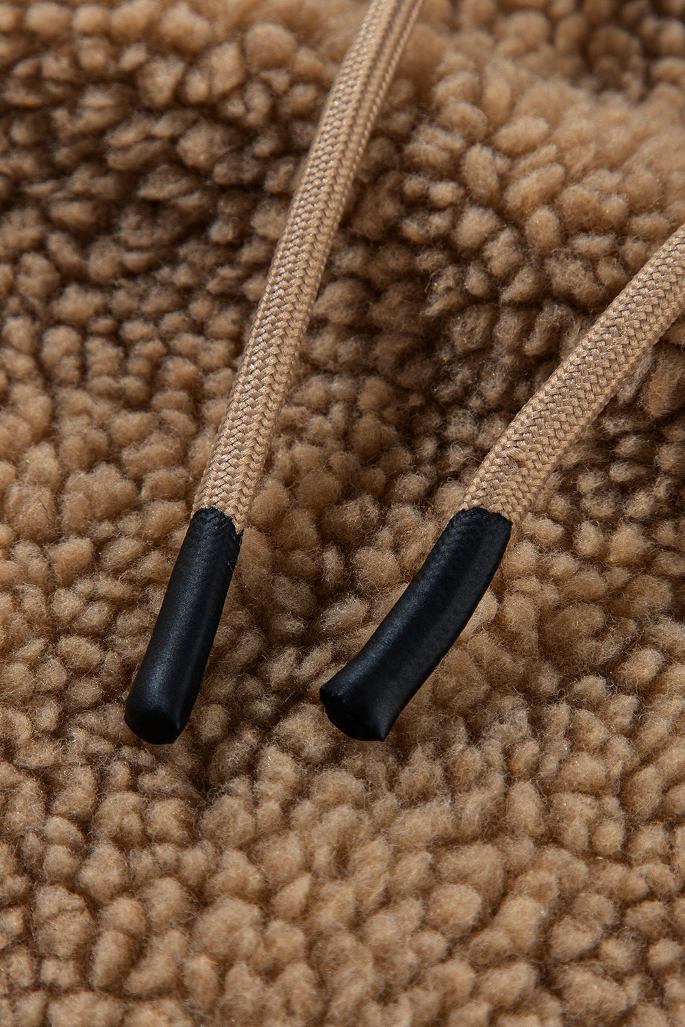 Brown sherpa hooded jacket detail with tan drawstrings and black tips.