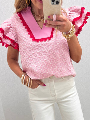 Pink eyelet embroidered blouse with flutter sleeves, contrast collar and red lace trim.