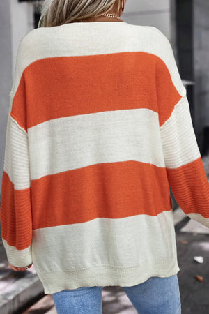 Orange and cream striped slouchy knit sweater with V-neck and ribbed sleeves.