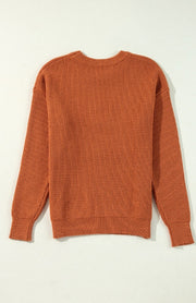 Terracotta knit sweater with ribbed texture and crew neck.