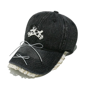 Black denim baseball cap with puppy appliqué, lace trim, and bow details.