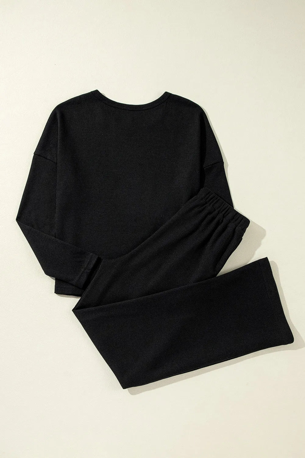 Black ribbed loungewear set with crewneck top and wide-leg pants.
