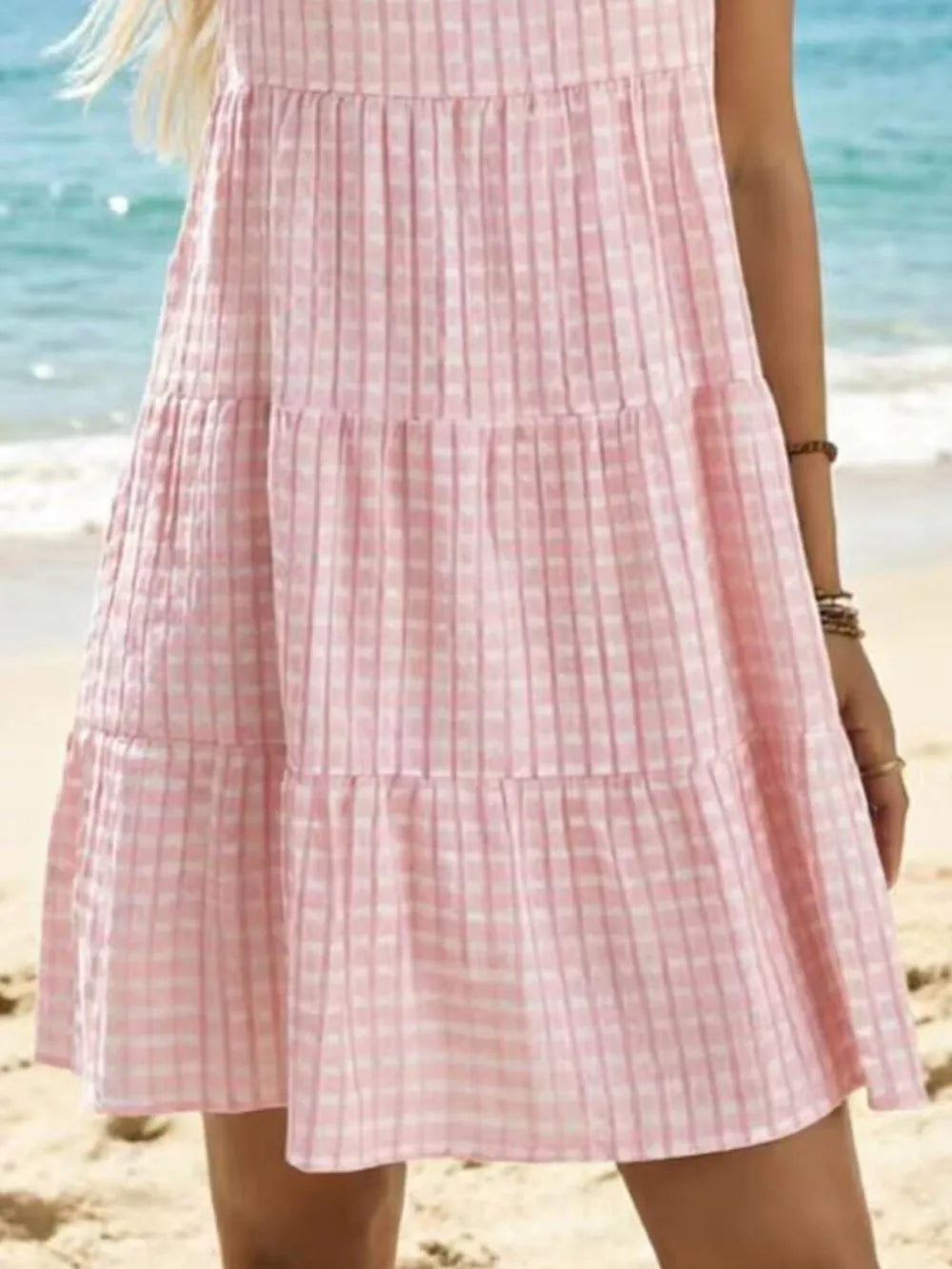 Pink tiered mini dress with a subtle checkered texture and a ruffled hem.