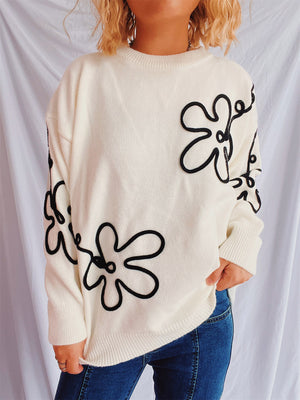 Beige knit sweater with black floral outline pattern, crew neck, long sleeves.