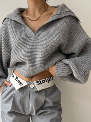 Gray knit sweater with wide collar and balloon sleeves, V-neck, ribbed texture.