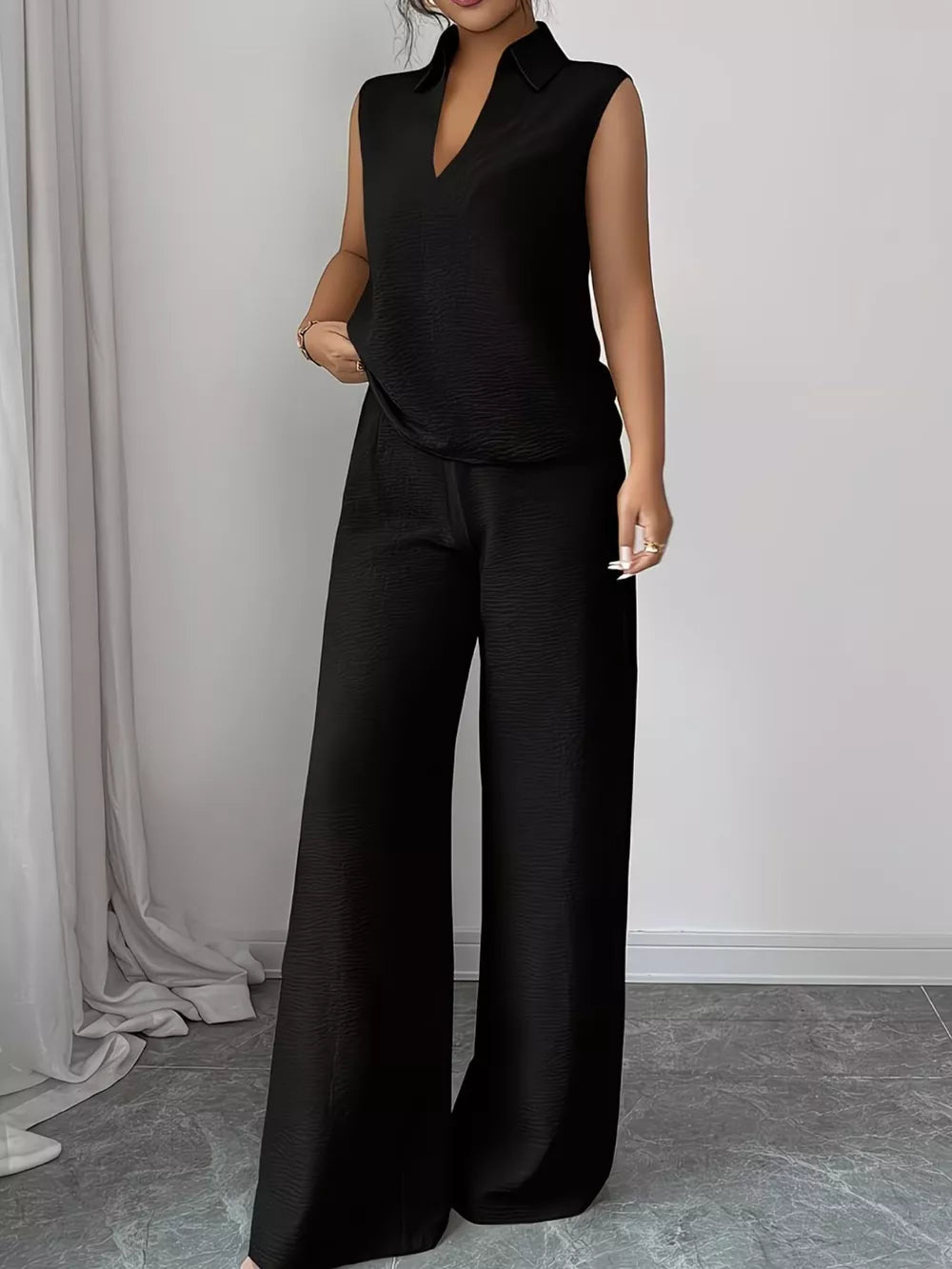 Black sleeveless collared V-neck top with textured fabric and matching wide-leg pants.