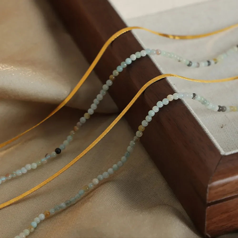 Gold layered necklace set with small light blue and tan beads and yellow ribbon detail