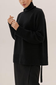 Black cashmere turtleneck sweater with raglan sleeves and ribbed cuffs and hem.