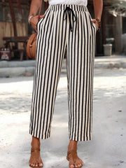 High-waisted cropped pants with black and white vertical stripes, drawstring, and pockets.