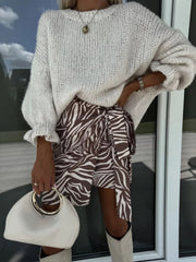 Cream voluminous sleeve knit sweater with ruffled cuffs, styled with a zebra print wrap skirt.