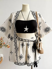 White polyester shorts and open cardigan set with black embroidered pattern and tassel belt.