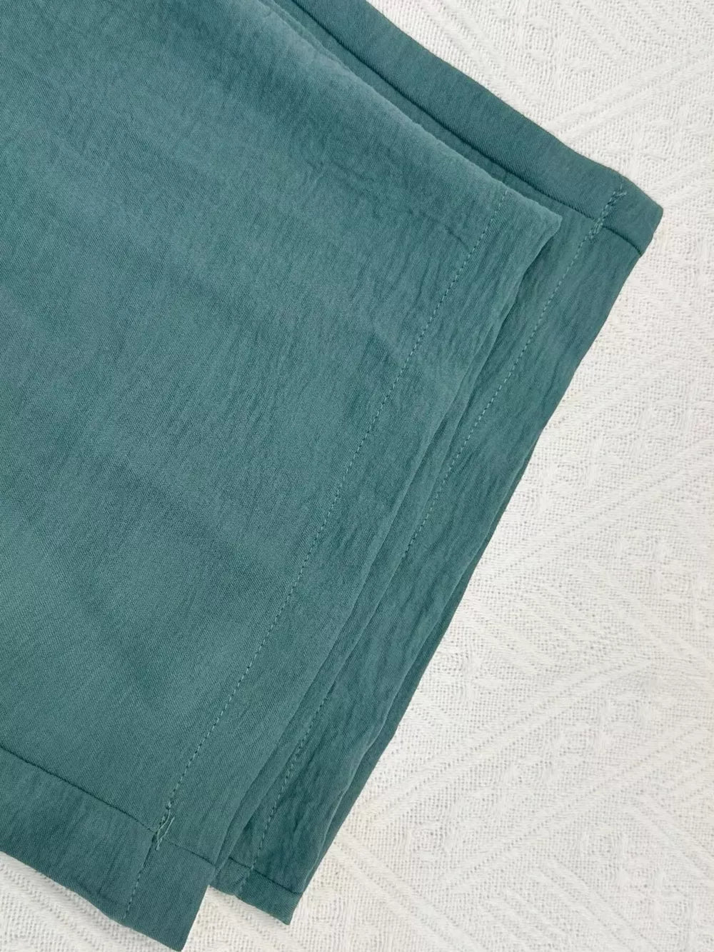 Turquoise cropped vest and wide-leg pants ensemble, textured fabric detail.