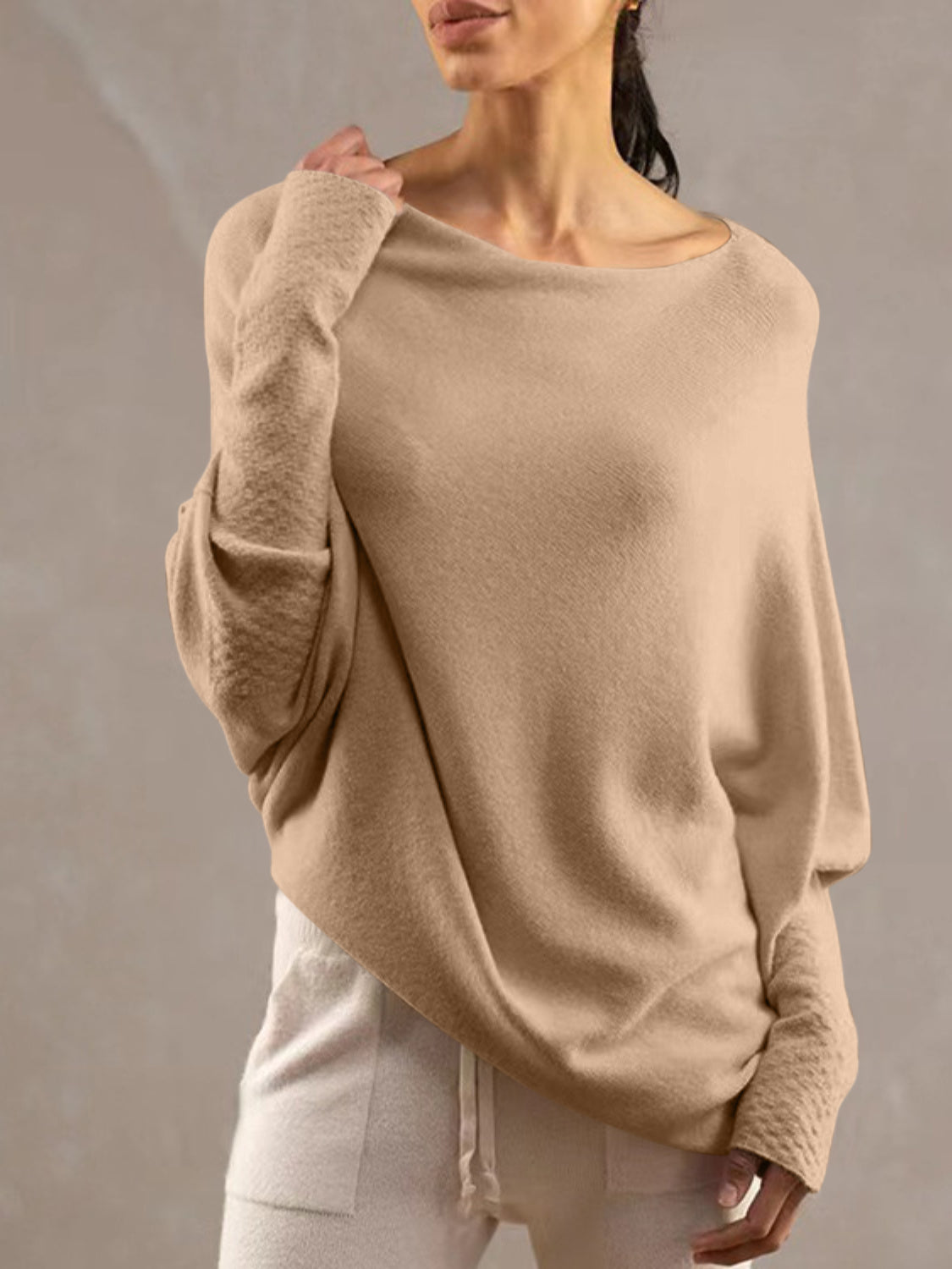 Off-shoulder knit sweater in cream with textured cuffs and batwing sleeves.