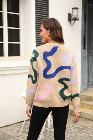 Tan crewneck sweater with abstract swirl pattern in blue, green, and pink.