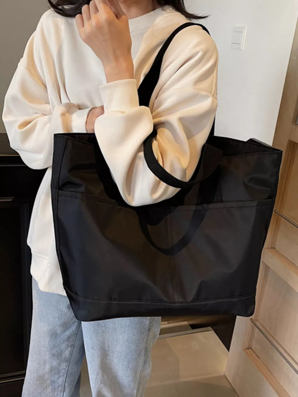 Black Oxford cloth shoulder tote bag with exterior pockets and black straps.