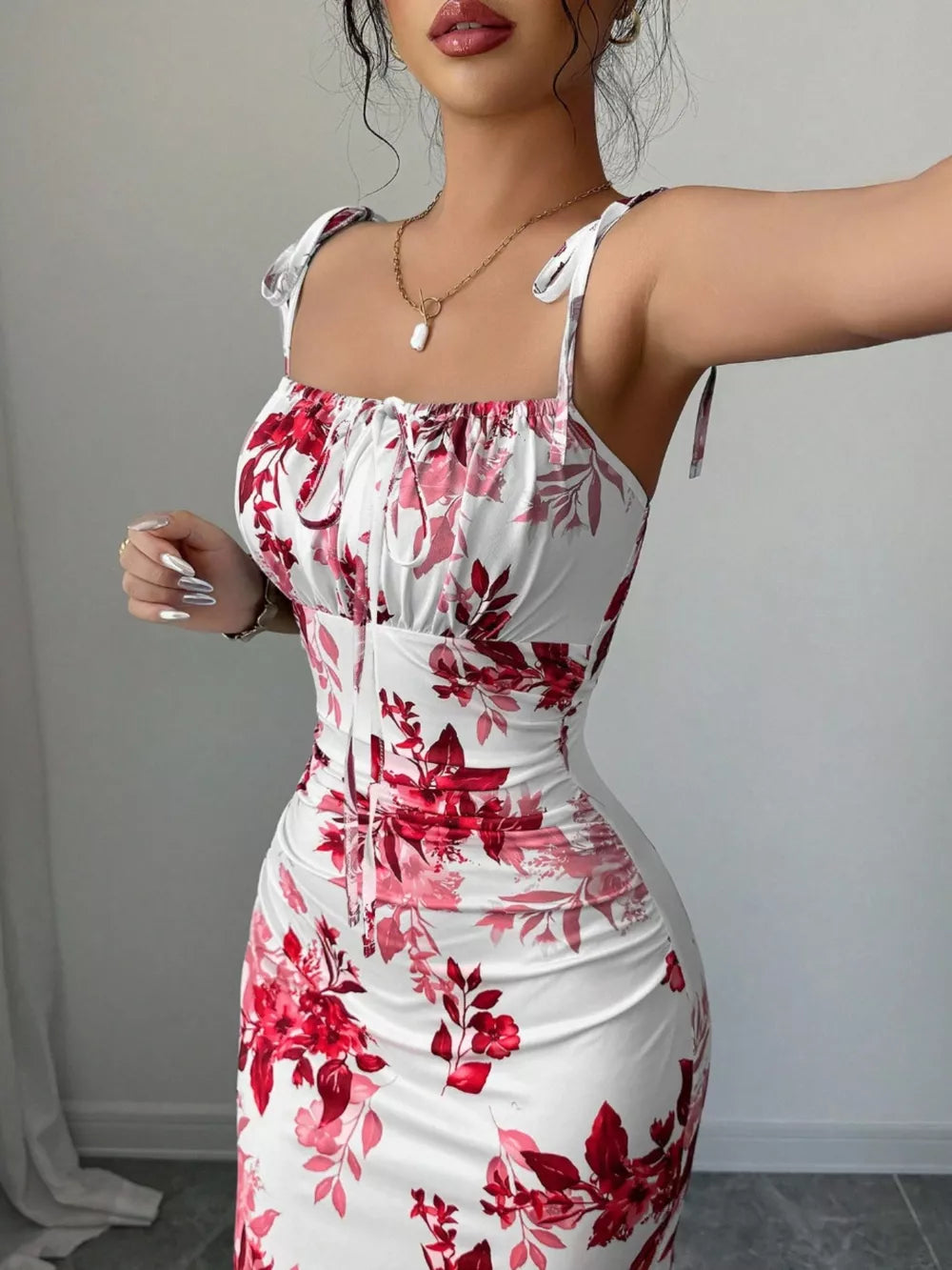 Floral print maxi dress in white with red and pink flowers, tie straps, and ruched bodice.