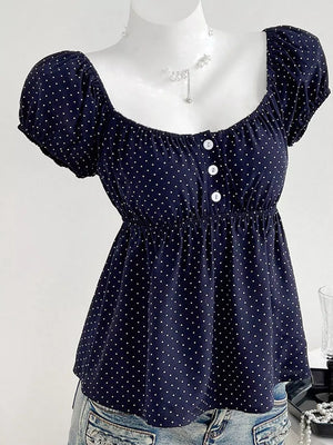 Navy polka dot puff sleeve shirt with square neckline and decorative buttons.