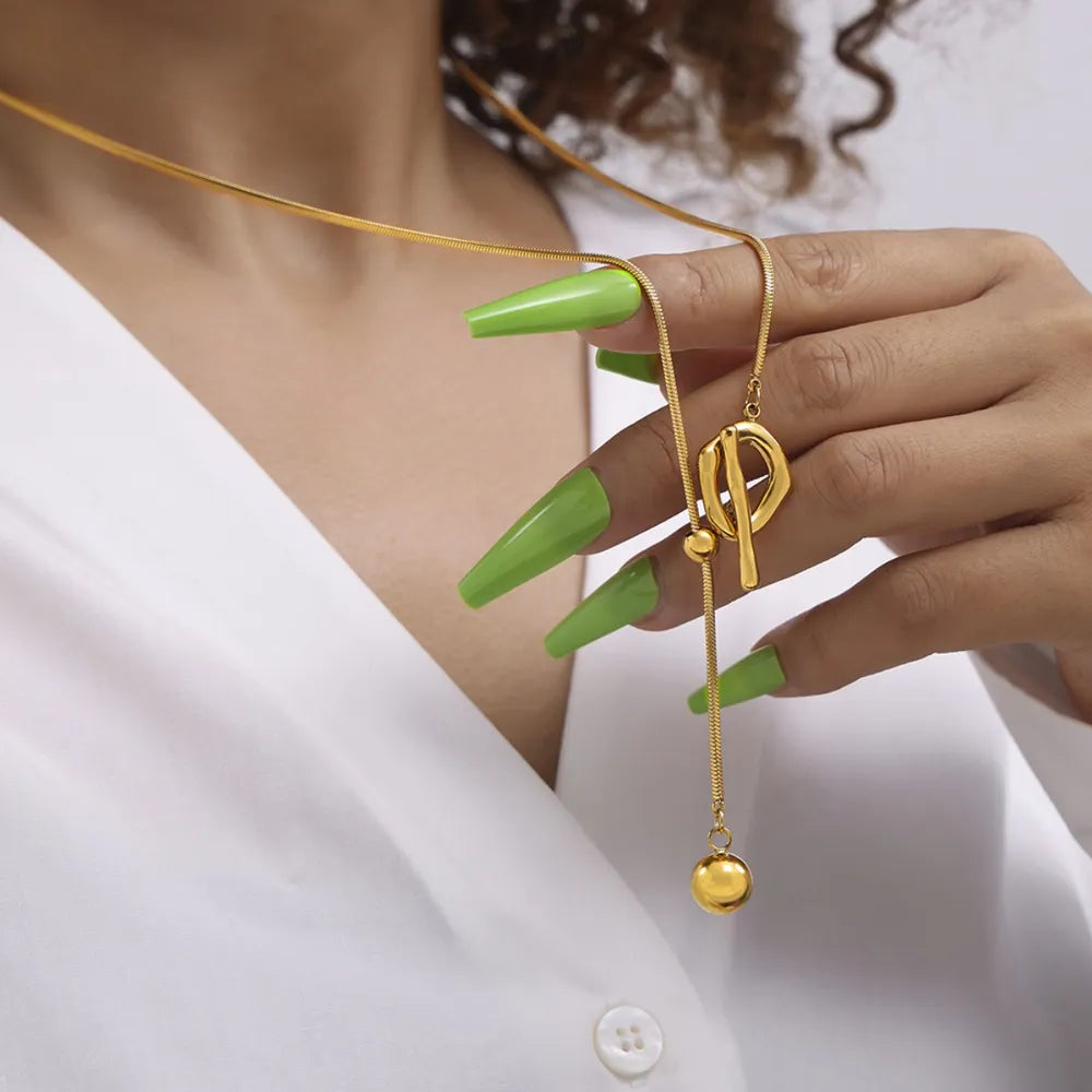 Gold lariat necklace with toggle clasp and ball pendant on a snake chain.