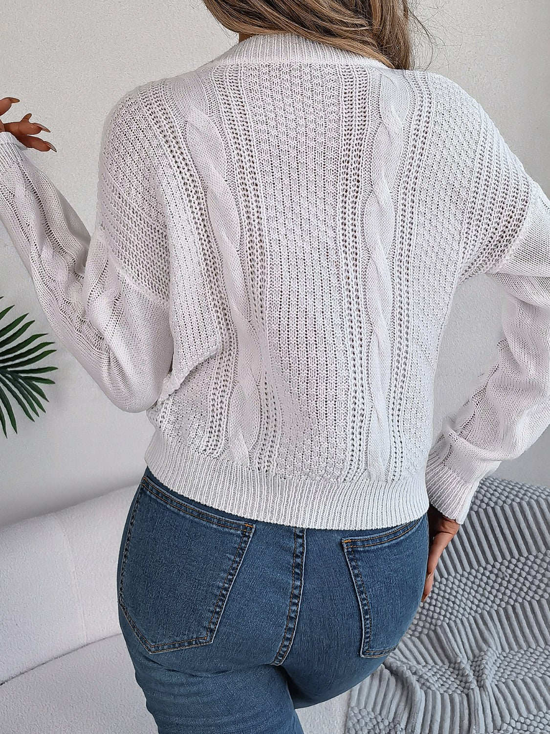 White cable knit sweater with open knit details and ribbed hem.