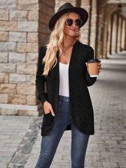 Black textured ribbed open-front cardigan with pockets, styled casually.