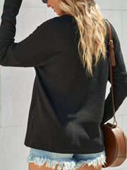 Black textured cotton henley shirt with long sleeves and button detail, styled with denim shorts.